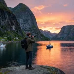 Beeindruckendes Urlaubserlebnis in Skandinavien, das einen Reisenden bei Sonnenuntergang während der Erkundung eines Fjords einfängt.